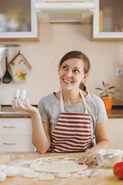 Köfte mutfak için mutlu kadın un ve bir hamur içinde bir cam dışarı kesim ile bir masada oturan bir genç güzel daireler. Pişirme ev. Yemek hazırlamak.