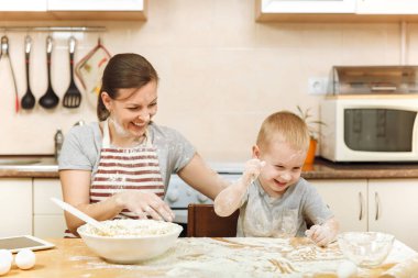 Küçük çocuk çocuk anne Noel masanın üzerine tablet ile ışık mutfakta zencefilli bisküvi pişirmek için yardımcı olur. Mutlu aile anne 30-35 yıl ve çocuk 2-3 eğlenmek ve un eve atmak. İlişki kavramı