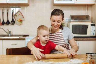 Küçük çocuk çocuk anne Noel ışık mutfakta zencefilli bisküvi pişirmek için yardımcı olur. Mutlu aile anne 30-35 yıl ve 2-3 rulo dışarı hamur ve çerezler de uygunbir çocuk ev. İlişki ve sevgi kavramı