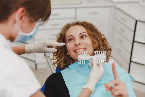 Dentist comparing patient\'s teeth shade with samples for bleaching treatment