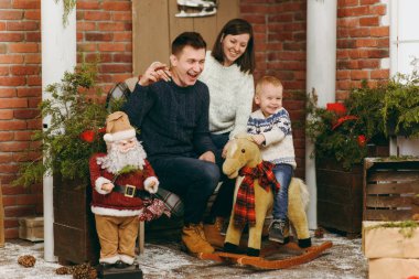 Mutlu anne şirin küçük bir çocuk çocuk sallanan at, tarih ile giyinmiş kazaklı odasında dekore edilmiş yeni yıl Noel Baba evde. Noel keyfi. Yaşam tarzı, Aile ve tatil 2018 kavramı