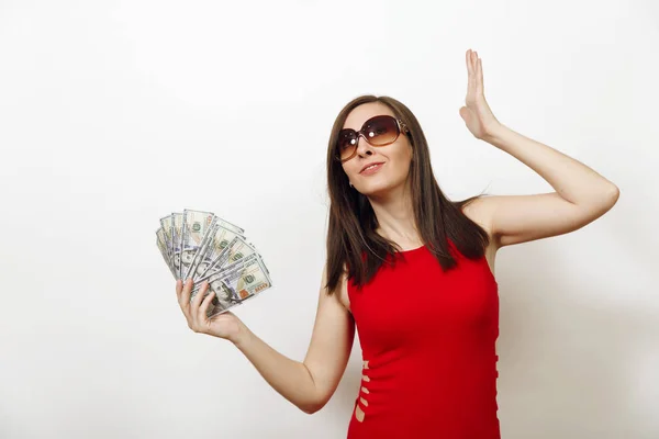 Jolie caucasienne jeune femme d'affaires heureuse en robe rouge et lunettes tenant billets d'argent sur fond blanc. Belle fille avec argent regardant de côté isolé . — Photo