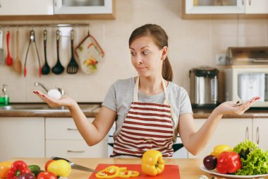 Tavuk ve bıldırcın arasında genç bir çekici dalgın kadın apronda seçer yumurta mutfakta. Diyet kavramı. Sağlıklı bir yaşam tarzı. Evde yemek. Yemek hazırlamak.
