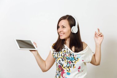 Güzel duygusal Avrupa kahverengi saçlı bir kadınla sağlıklı temiz cilt, büyüleyici smile, rahat hafif kıyafetler giymiş, dinler ve beyaz zemin üzerine tablet ile kulaklıklar müzik hoşlanır.