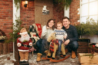 Mutlu anne şirin küçük bir çocuk çocuk sallanan at, tarih ile giyinmiş kazaklı odasında dekore edilmiş yeni yıl Noel Baba evde. Noel keyfi. Yaşam tarzı, Aile ve tatil 2018 kavramı