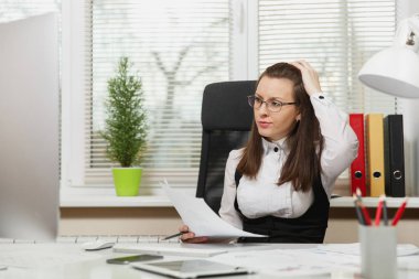 Takım elbise ve tablet ile masaya oturan gözlük güzel ciddi ve dalmış Kahverengi saç iş kadını ışık Office belgeleri ile modern monitör bilgisayarda çalışan bir kenara arıyorsunuz