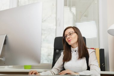 Takım elbise ve tablet ile masaya oturan gözlük güzel ciddi ve dalmış Kahverengi saç iş kadını ışık Office belgeleri ile modern monitör bilgisayarda çalışan bir kenara arıyorsunuz