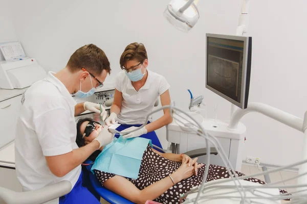 En manlig tandläkare med en kvinnlig assistent hjälper till att behandla tänderna — Stockfoto