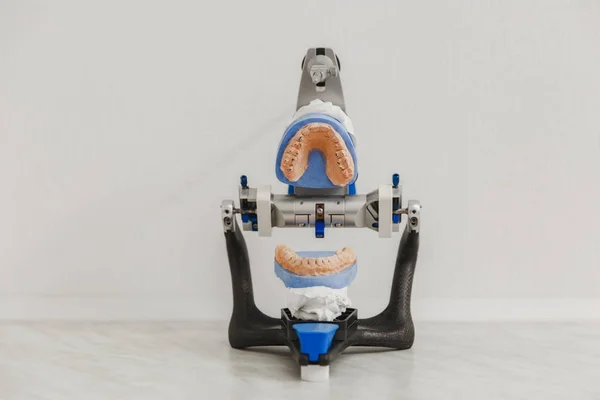 Артикулятор в стоматологической лаборатории с открытой плесенью или протезом в стоматологической лаборатории на белом фоне крупным планом — стоковое фото