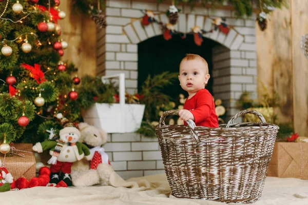 Πορτρέτο της παιχνιδιάρικο ευτυχισμένη χαριτωμένο μικρό μωρό αγόρι, που κάθεται στο καλάθι σε ένα διακοσμημένο δωμάτιο στο σπίτι. Χριστούγεννα καλή διάθεση. Το νέο έτος. Τρόπου ζωής, της οικογένειας και της συναδέλφωσης έννοια. — Φωτογραφία Αρχείου