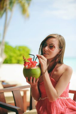 Maldivler sahilde bir pembe çiçek ile süslü masada yeşil Hindistan cevizi lezzetli kokteyl