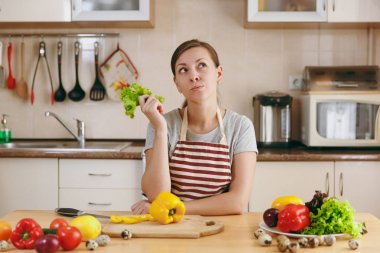 Bir genç çekici dalgın kadın apronda marul yaprağı mutfakta. Diyet kavramı. Sağlıklı bir yaşam tarzı. Evde yemek. Yemek hazırlamak.