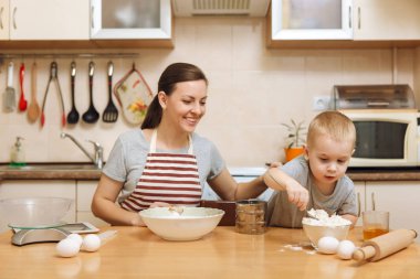 Küçük çocuk çocuk anne Noel masanın üzerine tablet ile ışık mutfakta zencefilli bisküvi pişirmek için yardımcı olur. Mutlu aile anne 30-35 yıl ve çocuk 2-3 hafta sonu sabah evde. İlişki kavramı