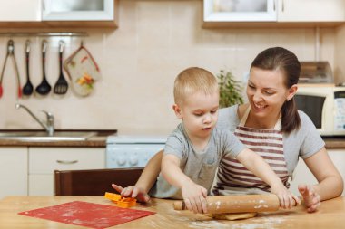 Küçük çocuk çocuk anne Noel ışık mutfakta zencefilli bisküvi pişirmek için yardımcı olur. Mutlu aile anne 30-35 yıl ve 2-3 rulo dışarı hamur ve çerezler de uygunbir çocuk ev. İlişki ve sevgi kavramı