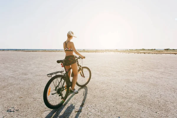 Silna Kobieta blonde w garnitur wielobarwny siada na rower — Zdjęcie stockowe
