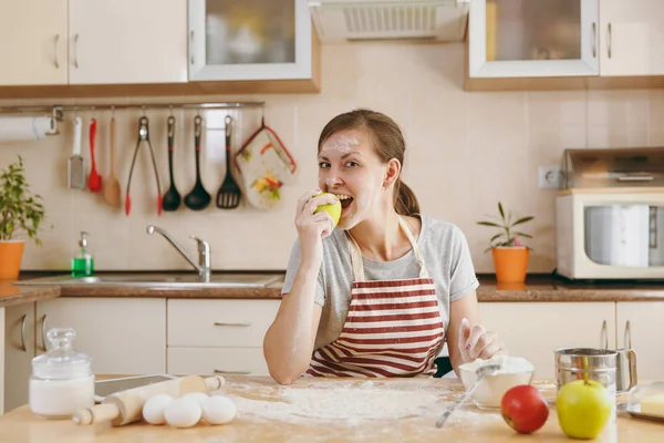 Eine junge, schöne, glückliche Frau sitzt an einem Tisch mit Mehl und bereitet in der Küche einen Weihnachtskuchen zu. Kochen zu Hause. Essen zubereiten. — Stockfoto