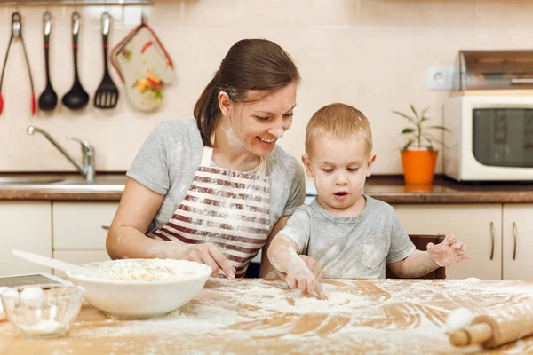 Niño pequeño ayuda a la madre a cocinar galletas de jengibre de Navidad en la cocina ligera con la tableta en la mesa. Feliz familia mamá 30-35 años y el niño 2-3 en la mañana del fin de semana en casa. Concepto de relación —  Fotos de Stock