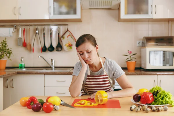 Молодая измученная уставшая женщина в фартуке готовит дома на кухне. Концепция диеты. Здоровый образ жизни. Готовьте еду. . — стоковое фото
