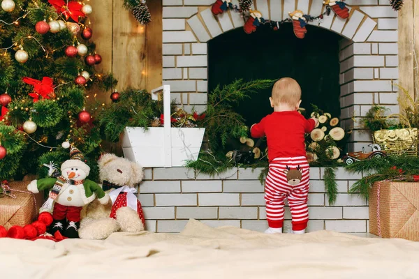 Πορτρέτο της παιχνιδιάρικο ευτυχισμένη χαριτωμένο μικρό μωρό αγόρι με κόκκινα ρούχα κοντά στο τζάκι σε ένα διακοσμημένο δωμάτιο στο σπίτι. Χριστούγεννα καλή διάθεση. Το νέο έτος. Τρόπου ζωής, της οικογένειας και της συναδέλφωσης έννοια. — Φωτογραφία Αρχείου