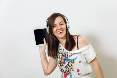 Güzel duygusal Avrupa kahverengi saçlı bir kadınla sağlıklı temiz cilt, büyüleyici smile, rahat hafif kıyafetler giymiş, dinler ve beyaz zemin üzerine tablet ile kulaklıklar müzik hoşlanır.