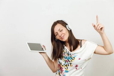 Güzel duygusal Avrupa kahverengi saçlı bir kadınla sağlıklı temiz cilt, büyüleyici smile, rahat hafif kıyafetler giymiş, dinler ve beyaz zemin üzerine tablet ile kulaklıklar müzik hoşlanır.