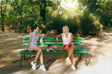 Anne ve kızı ile küçük komik köpek bankta oturmuş. L