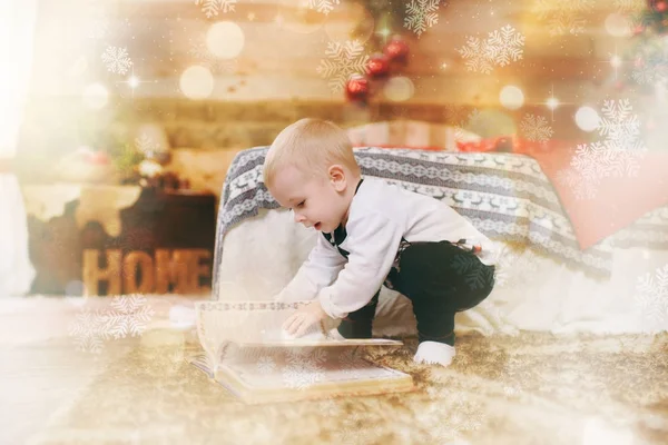 Niño pequeño en pijama blanco y negro en el suelo con cuentos de hadas cerca del árbol de Navidad en la habitación de madera decorada de Año Nuevo en casa. Concepto familia y vacaciones 2018. Efecto mágico resaltado — Foto de Stock