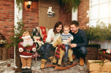 Mutlu anne şirin küçük bir çocuk çocuk sallanan at, tarih ile giyinmiş kazaklı odasında dekore edilmiş yeni yıl Noel Baba evde. Noel keyfi. Yaşam tarzı, Aile ve tatil 2018 kavramı