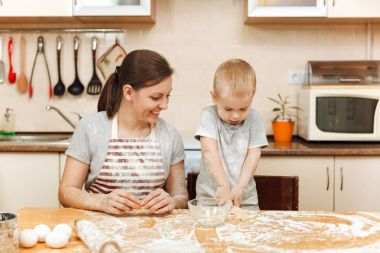 Küçük çocuk çocuk anne Noel masanın üzerine tablet ile ışık mutfakta zencefilli bisküvi pişirmek için yardımcı olur. Mutlu aile anne 30-35 yıl ve çocuk 2-3 hafta sonu sabah evde. İlişki kavramı
