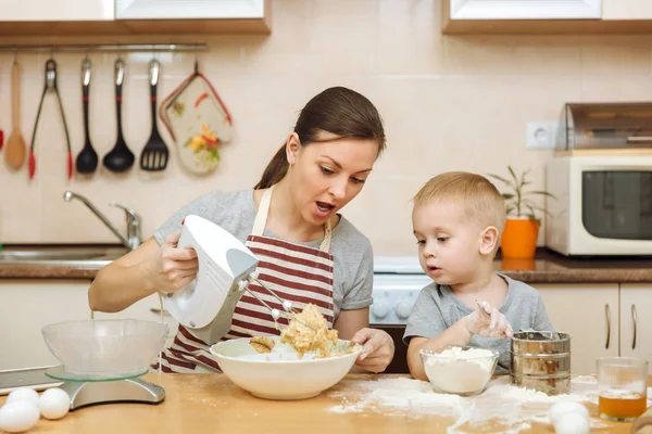 Küçük çocuk çocuk anne Noel masanın üzerine tablet ile ışık mutfakta zencefilli bisküvi pişirmek için yardımcı olur. Mutlu aile anne 30-35 yıl ve çocuk 2-3 hafta sonu sabah evde. İlişki kavramı