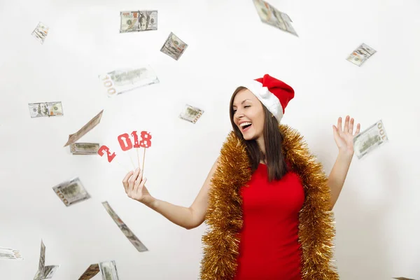 赤いドレス、見掛け倒し、白い背景の上カード番号 2018 や紙幣のお金を保持しているクリスマス帽子でかなり白人若い幸せな女。分離された現金を持つサンタ少女。新年休日 2018 コンセプト — ストック写真