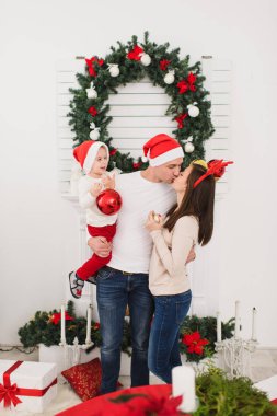 Şapkalı şirin küçük oğluyla mutlu anne. Büyük kırmızı Ağaç oyuncak topu ayakta dekore edilmiş yeni yıl ışık Oda evde Noel çelenk arka plan üzerinde çocuk çocuk. Aile, tatil 2018 kavramı.