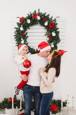 Şapkalı şirin küçük oğluyla mutlu anne. Büyük kırmızı Ağaç oyuncak topu ayakta dekore edilmiş yeni yıl ışık Oda evde Noel çelenk arka plan üzerinde çocuk çocuk. Aile, tatil 2018 kavramı.