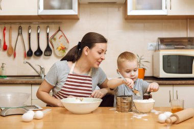 Küçük çocuk çocuk anne Noel masanın üzerine tablet ile ışık mutfakta zencefilli bisküvi pişirmek için yardımcı olur. Mutlu aile anne 30-35 yıl ve çocuk 2-3 hafta sonu sabah evde. İlişki kavramı