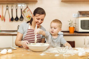 Küçük çocuk çocuk anne Noel masanın üzerine tablet ile ışık mutfakta zencefilli bisküvi pişirmek için yardımcı olur. Mutlu aile anne 30-35 yıl ve çocuk 2-3 hafta sonu sabah evde. İlişki kavramı