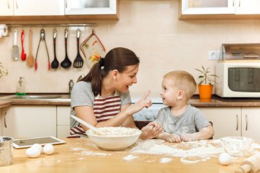 Küçük çocuk çocuk anne Noel masanın üzerine tablet ile ışık mutfakta zencefilli bisküvi pişirmek için yardımcı olur. Mutlu aile anne 30-35 yıl ve çocuk 2-3 hafta sonu sabah evde. İlişki kavramı