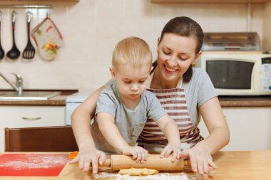 Küçük çocuk çocuk anne Noel ışık mutfakta zencefilli bisküvi pişirmek için yardımcı olur. Mutlu aile anne 30-35 yıl ve 2-3 rulo dışarı hamur ve çerezler de uygunbir çocuk ev. İlişki ve sevgi kavramı