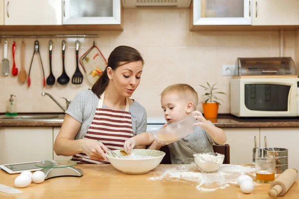 Küçük çocuk çocuk anne Noel masanın üzerine tablet ile ışık mutfakta zencefilli bisküvi pişirmek için yardımcı olur. Mutlu aile anne 30-35 yıl ve çocuk 2-3 hafta sonu sabah evde. İlişki kavramı