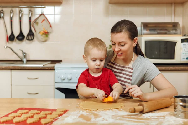 Küçük çocuk çocuk anne Noel ışık mutfakta zencefilli bisküvi pişirmek için yardımcı olur. Mutlu aile anne 30-35 yıl ve 2-3 rulo dışarı hamur ve çerezler de uygunbir çocuk ev. İlişki ve sevgi kavramı
