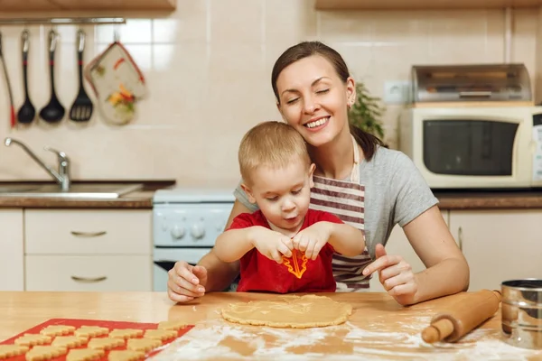Küçük çocuk çocuk anne Noel ışık mutfakta zencefilli bisküvi pişirmek için yardımcı olur. Mutlu aile anne 30-35 yıl ve 2-3 rulo dışarı hamur ve çerezler de uygunbir çocuk ev. İlişki ve sevgi kavramı