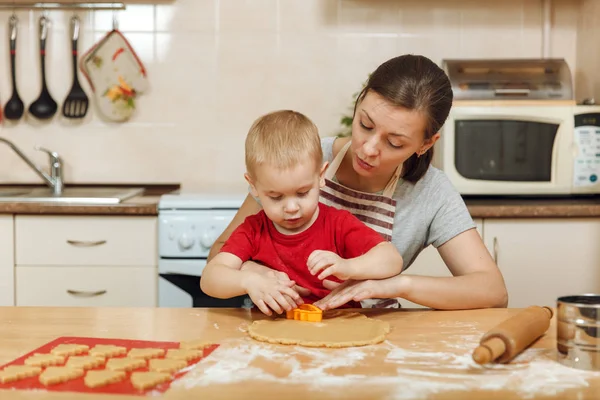 Küçük çocuk çocuk anne Noel ışık mutfakta zencefilli bisküvi pişirmek için yardımcı olur. Mutlu aile anne 30-35 yıl ve 2-3 rulo dışarı hamur ve çerezler de uygunbir çocuk ev. İlişki ve sevgi kavramı