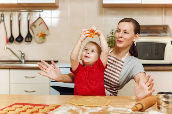 Küçük çocuk çocuk anne Noel ışık mutfakta zencefilli bisküvi pişirmek için yardımcı olur. Mutlu aile anne 30-35 yıl ve 2-3 rulo dışarı hamur ve çerezler de uygunbir çocuk ev. İlişki ve sevgi kavramı