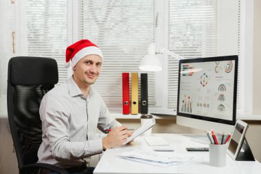 Gömlek ve kırmızı Noel şapka adam yakışıklı gülümseyen iş oturmak