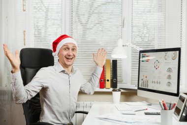 Gömlek ve kırmızı Noel şapka adam yakışıklı gülümseyen iş oturmak