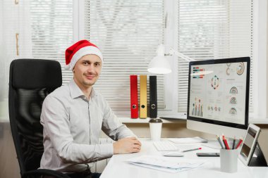 Gömlek ve kırmızı Noel şapka adam yakışıklı gülümseyen iş oturmak