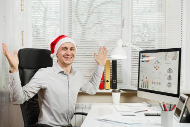 Gömlek ve kırmızı Noel şapka adam yakışıklı gülümseyen iş oturmak