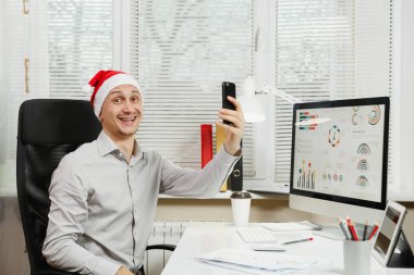 Gömlek ve kırmızı Noel şapka adam yakışıklı gülümseyen iş oturmak