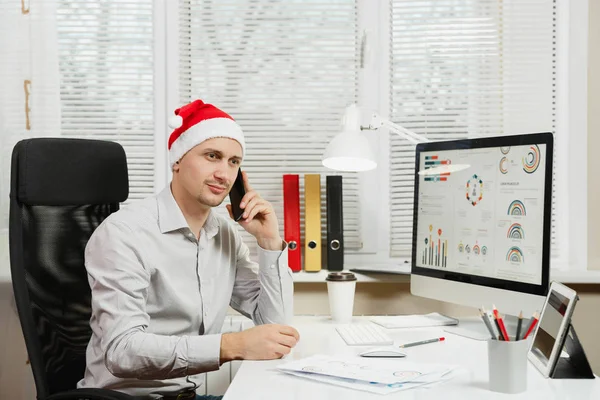 Yakışıklı iş adamı oturan gömlek ve kırmızı Noel şapkalı 