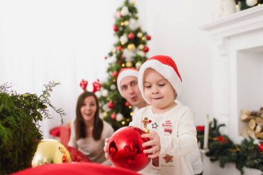 Şapkalı şirin küçük oğluyla mutlu anne. Büyük kırmızı Ağaç oyuncak topu ayakta dekore edilmiş yeni yıl ışık Oda evde çocuk çocuk. Noel keyfi. Aile, sevgi ve tatil 2018 kavramı.