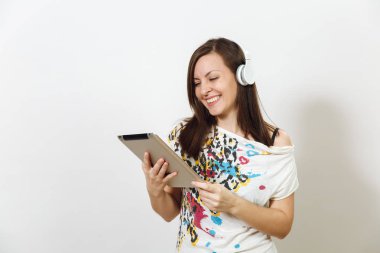 Güzel duygusal Avrupa kahverengi saçlı bir kadınla sağlıklı temiz cilt, büyüleyici smile, rahat hafif kıyafetler giymiş, dinler ve beyaz zemin üzerine tablet ile kulaklıklar müzik hoşlanır.